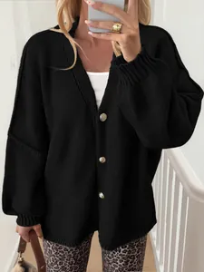 Detail of oversized black knit cardigan featuring elegant gold buttons for women.