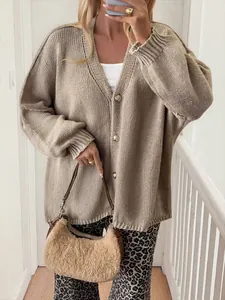 Close-up of stylish oversized beige knit cardigan featuring elegant gold buttons