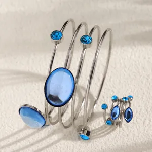 Detailed view of silver-tone wrap-around bracelet and ring set with blue gemstones