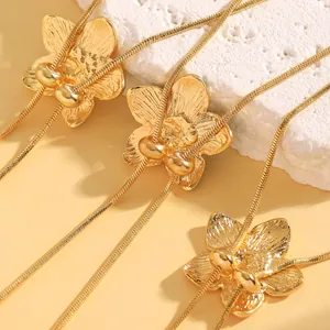 Detailed view of golden flower pendants with fine snake chains on a textured white stone.