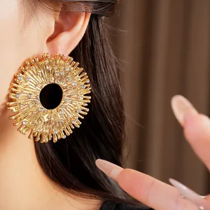 Vista ravvicinata di grandi orecchini a forma di sole dorato con strass sul modello