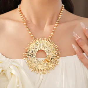Dettaglio ravvicinato di una grande collana con ciondolo a raggiera dorata e strass chiari
