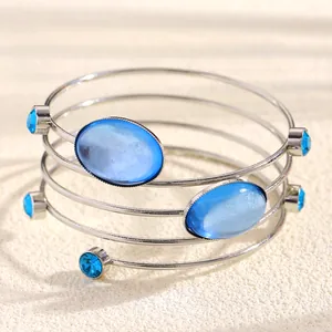 Detailed macro shot of a silver spiral bracelet with oval blue gemstones and small rhinestones