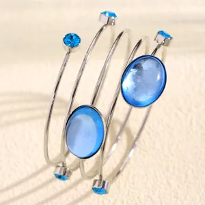 Close-up of multi-layer spiral bracelet with blue gemstones and rhinestones.
