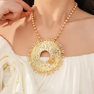 Vista dettagliata di una collana con ciondolo rotondo cavo dorato, strass e farfalla