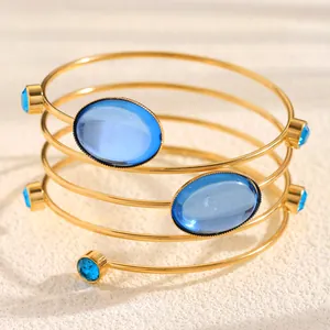 Detailed view of polished blue gemstones on a gold spiral wire wrapped open bangle