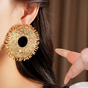 Primo piano di un grande orecchino dorato traforato con strass lucidi e brillanti