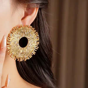 Primo piano dettagliato di un orecchino a raggiera dorato con strass su una modella.