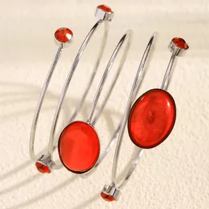 Close-up of elegant silver spiral bracelet with oval red gemstones and rhinestones