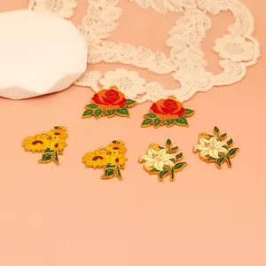 Detailed view of enamel flower charms featuring rose, sunflower, and lily designs.