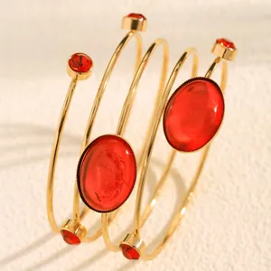 Detail of a French style spiral bangle featuring large oval red gemstones and gold finish