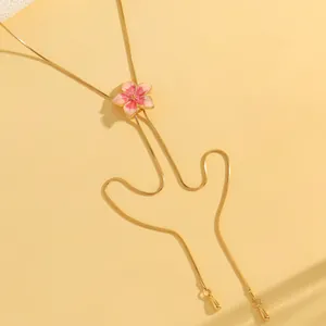 Macro view of the pink enamel flower pendant and delicate golden snake chain detail.