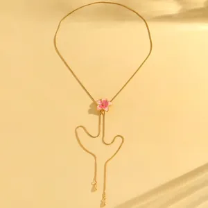 Close-up of a pink enamel flower pendant on a dainty gold snake chain necklace
