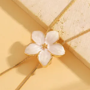 Exquisite macro detail of a beautiful white enamel flower pendant on a gold chain