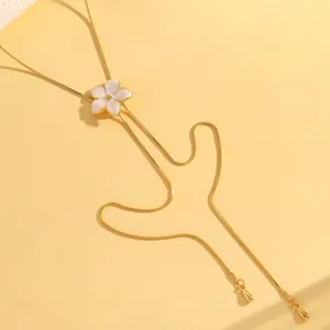 Detailed macro view of a sweet ocean style gold necklace with white enamel flower pendant.