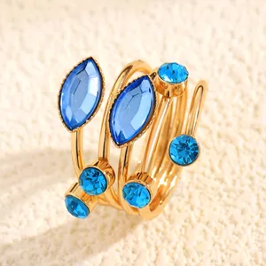 Close-up of gold wrap-around ring featuring marquise and round blue rhinestones.