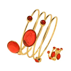 Detailed view of a gold-tone coiled bracelet and ring set with vibrant red gemstones.