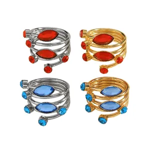Detailed view of spiral wrap-around rings with red and blue gemstones in gold and silver