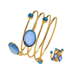 Close-up of elegant gold wrap-around bracelet and matching ring set with blue gemstones.