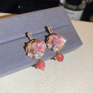 Gros plan détaillé de boucles d'oreilles bohèmes fleurs roses avec cristaux et perles.