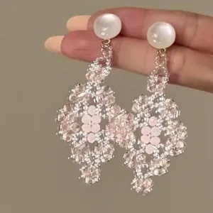 Gros plan de boucles d'oreilles pendantes fleurs roses en forme de losange