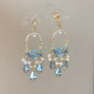 Boucles d'oreilles style cour vintage avec cristaux bleus et perles sur un support