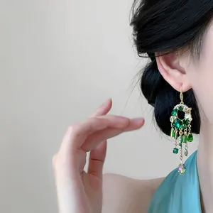 Vue détaillée de boucles d'oreilles style vintage avec pompons en cristal vert sur modèle