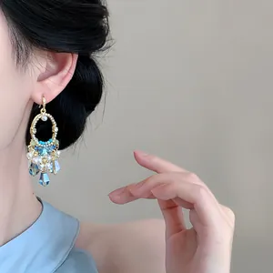 Gros plan de boucles d'oreilles dorées de style palais vintage avec glands en cristal bleu