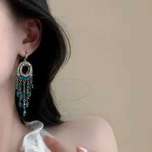 Gros plan de boucles d'oreilles style palais avec pampilles en cristal bleu-vert