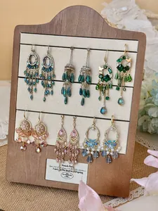 Boucles d'oreilles vintage style palais avec cristaux colorés sur un présentoir en bois.