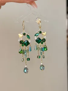Vue détaillée de boucles d'oreilles à pompons vert émeraude de style cour avec papillon