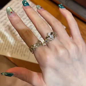 Close-up detail of exquisite vintage gold butterfly and iris fleur-de-lis open rings on finger