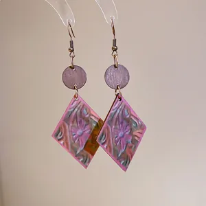 Detalle de primer plano del estampado floral vintage en pendientes de madera con forma de rombo