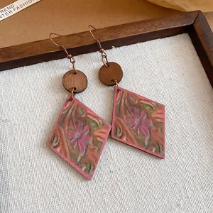Primer plano de pendientes vintage de madera en forma de rombo con estampado floral y ganchos