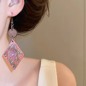 Primer plano de pendientes retro de madera en forma de rombo con estampado floral.