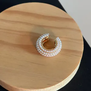 Detailed view of a luxury C-shaped gold ear cuff encrusted with small white pearls