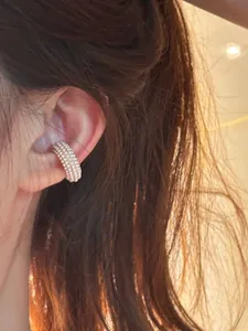 Close-up of an elegant C-shaped ear cuff decorated with multiple rows of white pearls