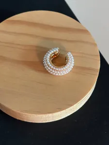 Detailed macro shot of an elegant pearl-encrusted C-shaped gold ear cuff