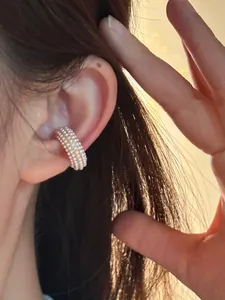 Detail showing a multi-row pearl C-shaped ear cuff worn on the ear bone, vintage style.