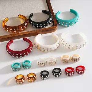 Dettaglio di anelli e bracciali in resina con rivetti metallici in vari colori vivaci