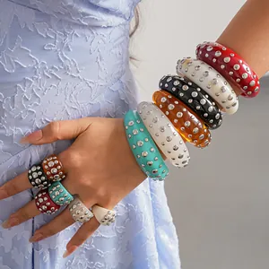Primo piano di bracciali e anelli in resina colorata con borchie in metallo