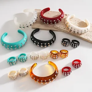 Vista dettagliata di bracciali e anelli in resina assortiti con borchie metalliche