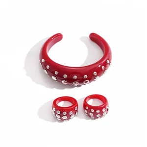 Set bracciale e anelli in resina rossa con borchie metalliche circolari argentate