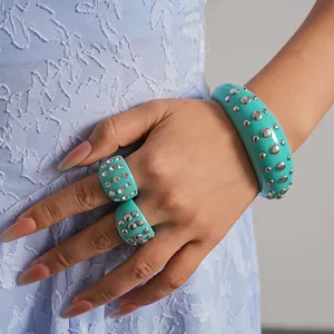Vista dettagliata di anelli e bracciale in resina turchese con rivetti argento.