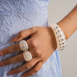 Vista dettagliata di bracciale e anelli in resina con borchie argentate e strass luccicanti