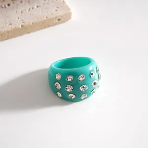 Primo piano di un anello in resina turchese con dettagli in strass scintillanti.