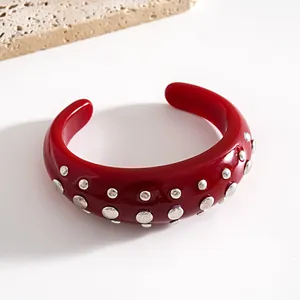 Vista dettagliata del bracciale rigido in resina rossa con borchie in metallo