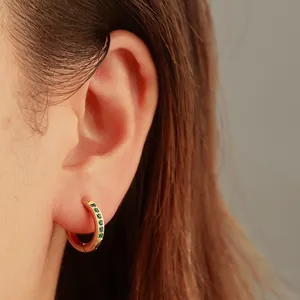 Détail d'une boucle d'oreille en acier inoxydable doré 18K avec zircons verts étincelants.