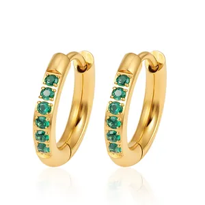Vue détaillée de boucles d'oreilles créoles dorées avec zircons verts étincelants