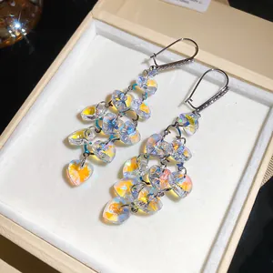 Close-up of iridescent heart-shaped crystal tassel earrings with zircon studs in jewelry box.